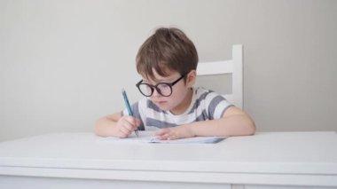 4k. little cute serious caucasian boy in glasses study, write
