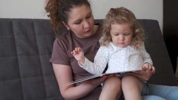 4k. Engraçado menina bonito com a mãe ler livros — Vídeo de Stock