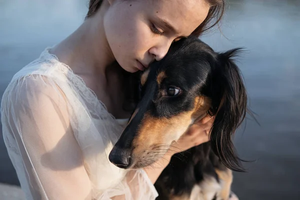 Attractive young woman holding saluki dogs face. close up portrait. — Stock Photo, Image