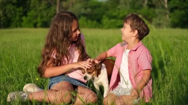 Brother and sister pet their dog outdoor — Stock Video