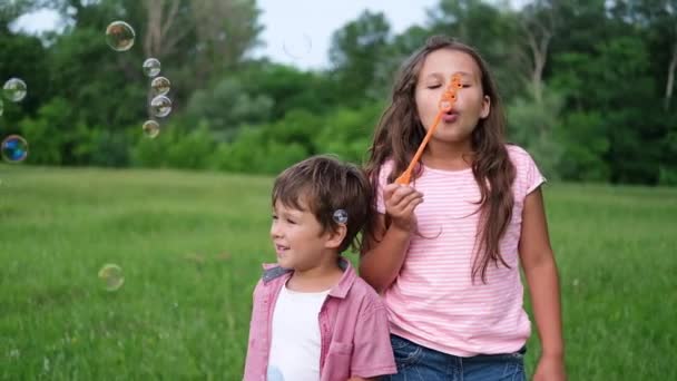 Broder och syster leker tillsammans blåser bubblor utomhus — Stockvideo