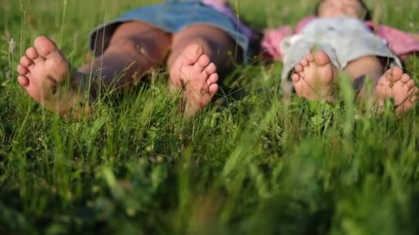 Счастливые двое детей босиком вместе в траве под открытым небом — стоковое видео