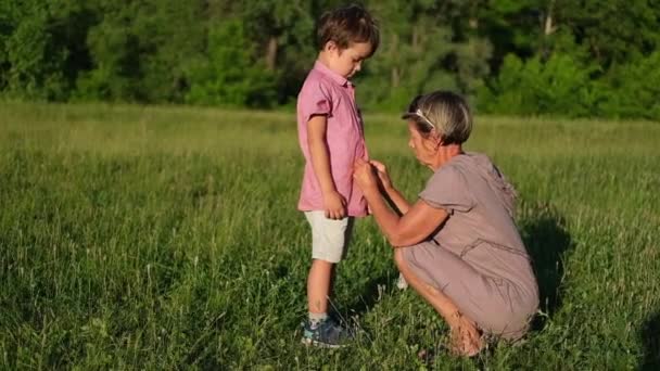 Grandmother buttoning up his shirt little caucasian boy — Stock Video