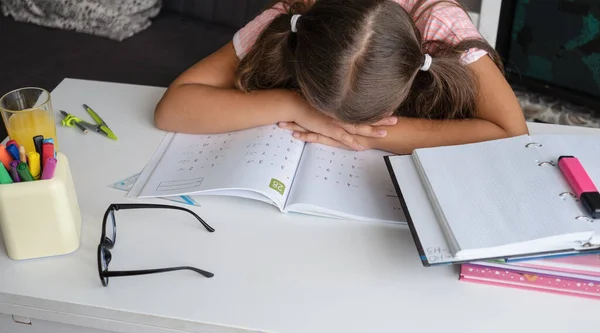Müdes, erschöpftes Mädchen liegt auf ihren Händen und macht Hausaufgaben — Stockfoto