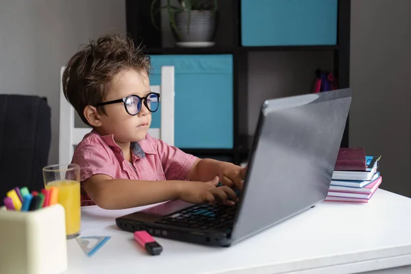 Menino caucasiano cansado usando laptop com óculos estudando em casa Imagens Royalty-Free