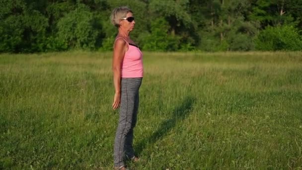 Active seniors woman begin fitness workout, squatting doing sit-ups in park — Stock Video