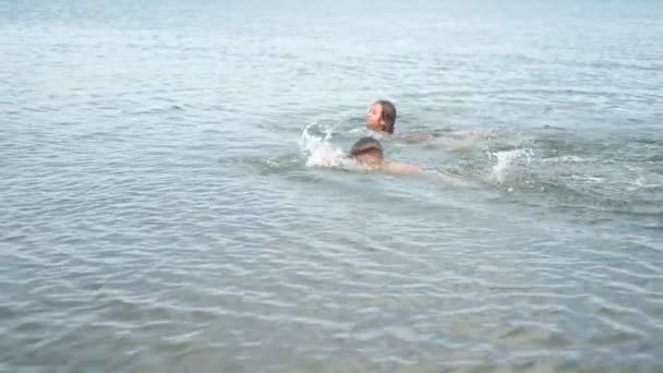 Joyful boy and girl swim in the water — 图库视频影像