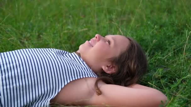 Feliz niña linda acostada en la hierba al aire libre — Vídeos de Stock