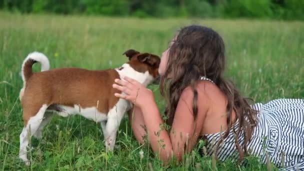 Lindo poco caucásico chica mascota su perro acostado en la hierba — Vídeos de Stock