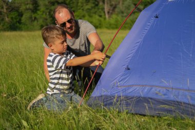 Baba oğluna çadır kurmayı öğretiyor.