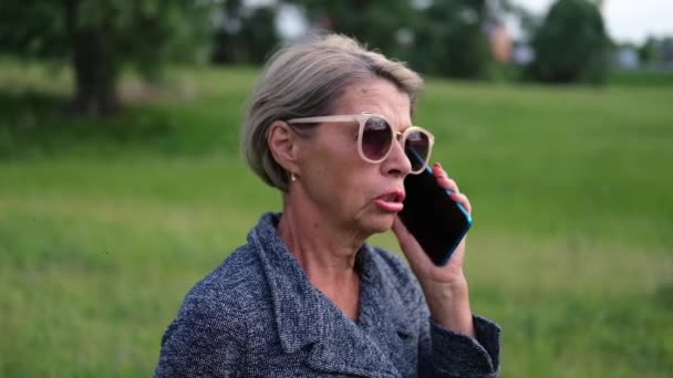Attractive senior business woman talking on phone, relax in park — Stock Video