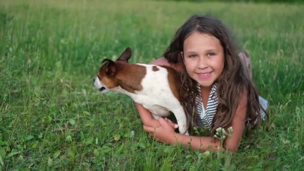 Bonito pouco caucasiano triste menina abraçar seu cão deitado na grama — Vídeo de Stock