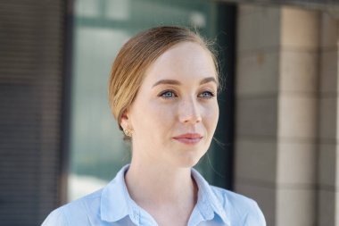 Gülümseyen genç iş kadını şehirde yürüyor 