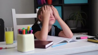 Yorgun, yorgun, kızıl saçlı kız. Ellerinin üzerine uzanmış, ödev yapıyor.