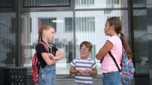Tři děti s batohem stát a mluvit spolu a dát pět — Stock video