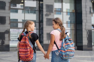  Sırt çantalı iki kız okula gider ve konuşurlar. 