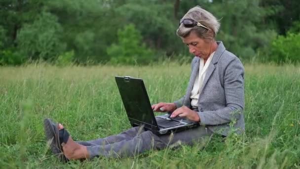 Aantrekkelijke senior zakenvrouw maken project op laptop, ontspannen in park — Stockvideo