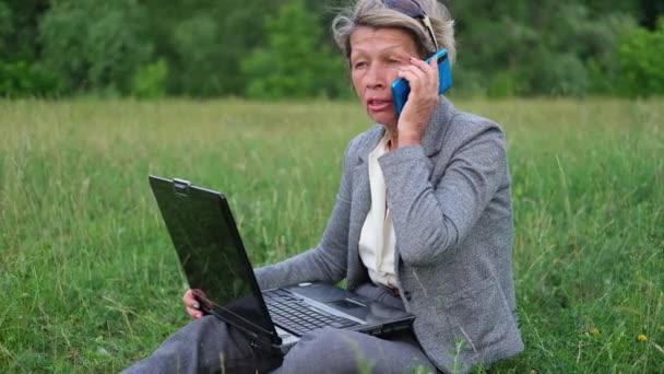 Attractive senior business woman make project on laptop, talk on phone in park — Stock Video