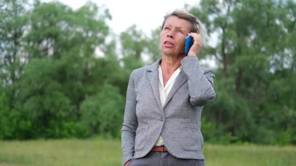 Atractiva mujer de negocios senior hablando por teléfono, relajarse en el parque — Vídeos de Stock