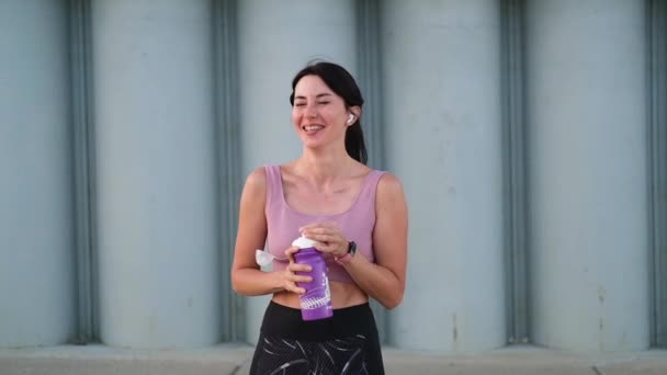 Joven mujer fitness terminar correr y beber agua y escuchar música — Vídeo de stock