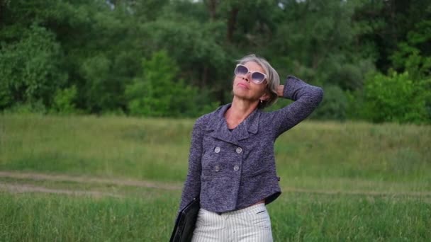 Attractive senior business woman walk in park with laptop — Stock Video