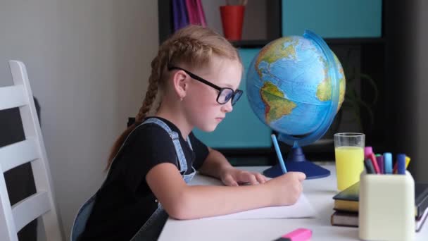 Gözlüklü, evde ders çalışan, ev ödevi yapan ciddi, beyaz saçlı bir kız. — Stok video