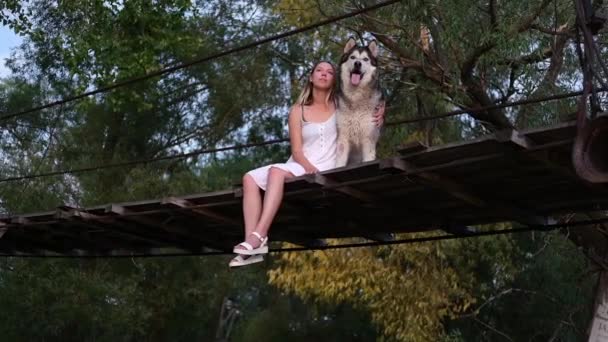 Happy woman embrace alaskan malamute dog on suspension bridge — Vídeo de Stock