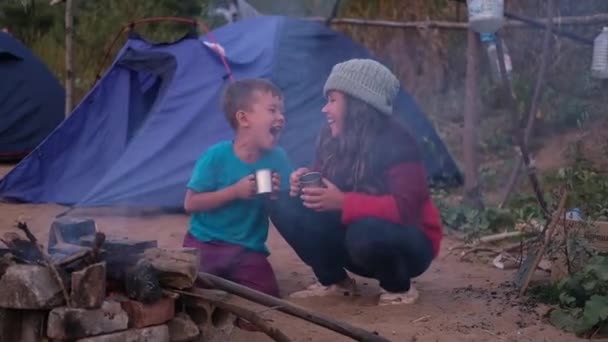 Två barn dricker varm choklad vid lägerelden i skogen — Stockvideo