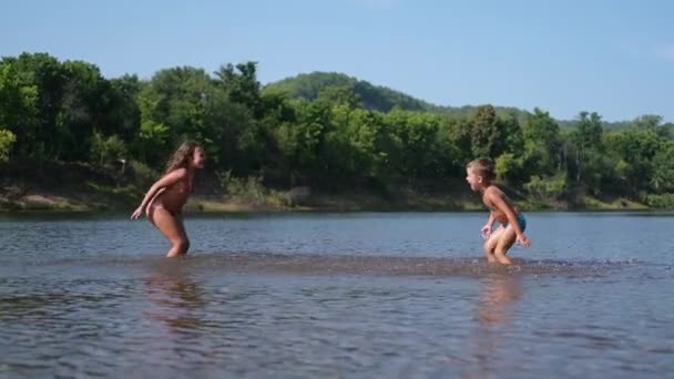 Gioioso felice ragazzo e ragazza giocare e spruzzato l'un l'altro in acqua — Video Stock