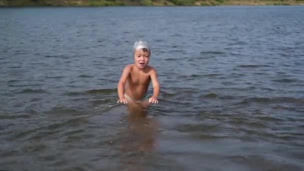 Kleines Kind schwimmt in Badekappe unter Wasser — Stockvideo