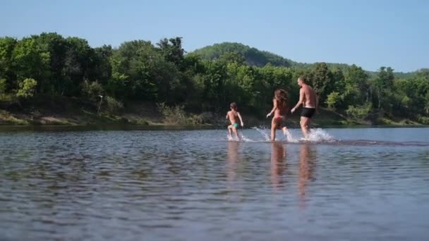 Радісний щасливий хлопчик і дівчинка грають і бігають у воді — стокове відео