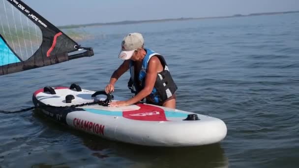 Ufa, Rusland, 13 augustus 2021, senior vrouw bereid zich voor op windsurfen — Stockvideo
