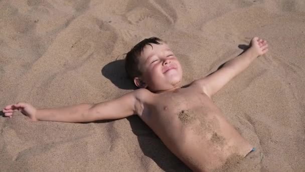 Niño feliz acostado y jugar en la arena de cerca. — Vídeos de Stock