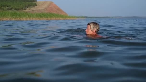 Aktive Seniorin im Badeanzug schwimmt im Wasser — Stockvideo