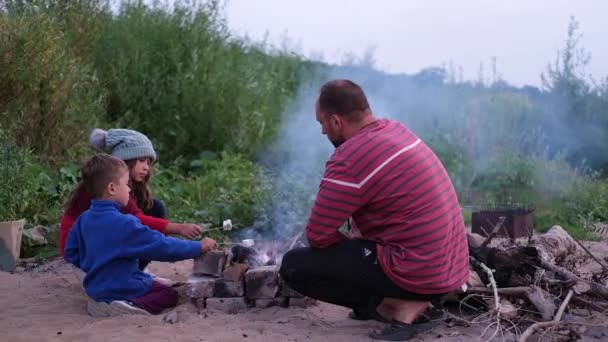 Dos niños con padre asando malvavisco en la fogata en el bosque — Vídeo de stock