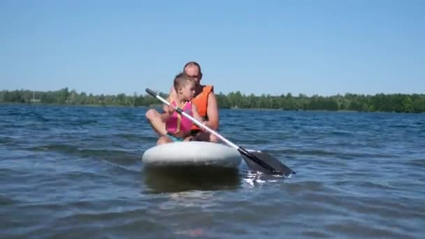 Ufa, Rusia, 14 de junio de 2021, niño pequeño con padre para montar en el tablero del charco — Vídeos de Stock