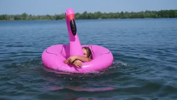 Fröhlich fröhliche Mädchen spielen und planschen mit Flamingo im Wasser — Stockvideo