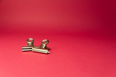 Pembe arka planın sol tarafında iki metal ataç var.