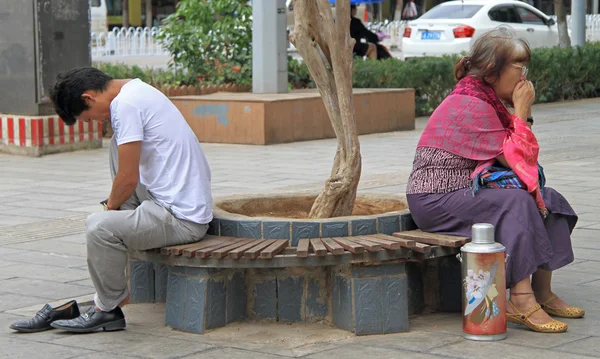 Muž a žena sedí na lavičce v parku, Kunming — Stock fotografie
