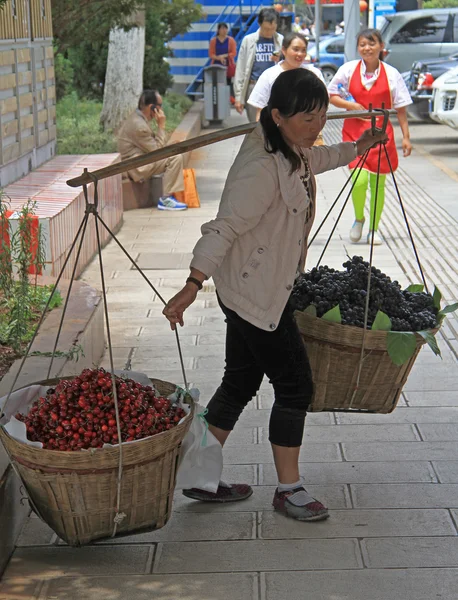 Mujer lleva dos mochilas con cerezas y uvas — Foto de Stock