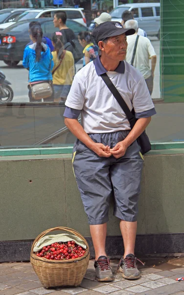 Člověk je prodej třešní na ulici v Kunming, Čína — Stock fotografie