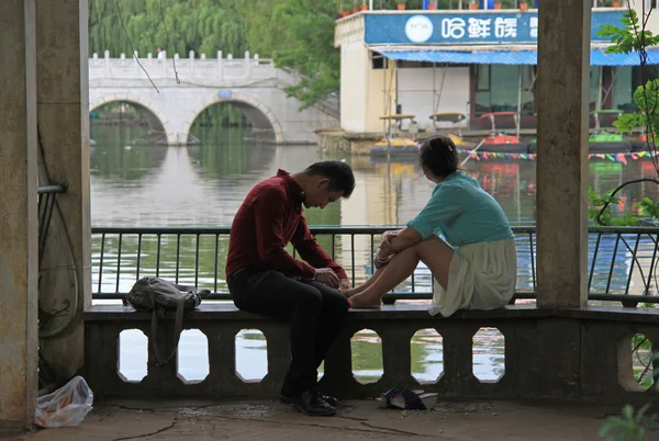 Niña y niño están sentados en un banco en el parque, Kunming, China — Foto de Stock