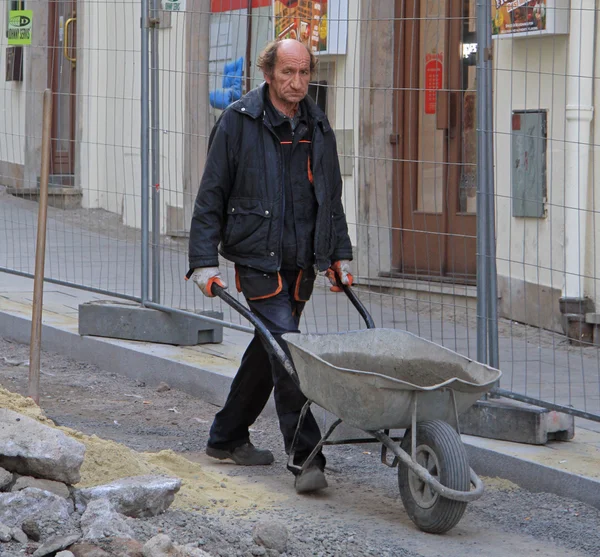 Hombre está llevando carretilla con cemento —  Fotos de Stock