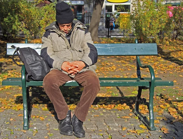 Człowiek jest w stanie spoczynku na ławce odkryty w Kraków, Polska — Zdjęcie stockowe