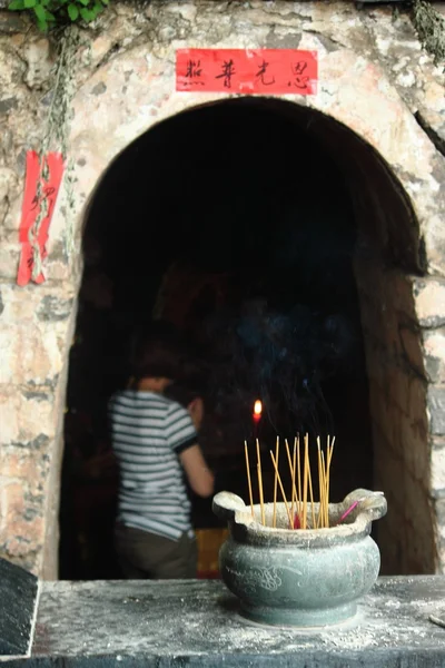 Firing candles and unfocused woman in buddhist cave — Stock Photo, Image