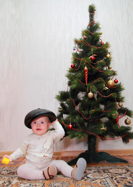 Bebé en peakes cap cerca de árbol de Navidad — Foto de Stock