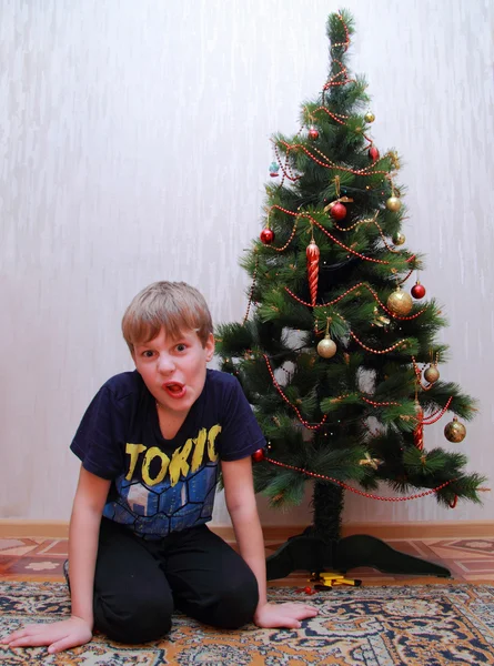 Niño con mueca divertida cerca del árbol de Navidad — Foto de Stock