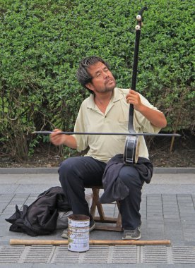blind musician is playing on the street in Shanghai clipart