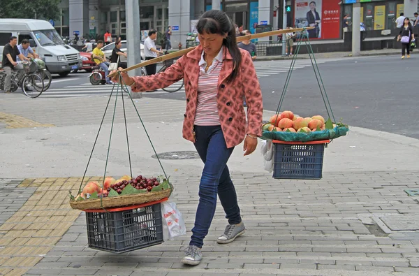 Mujer está llevando brazo de equilibrio con cestas de frutas en Shanghai — Foto de Stock