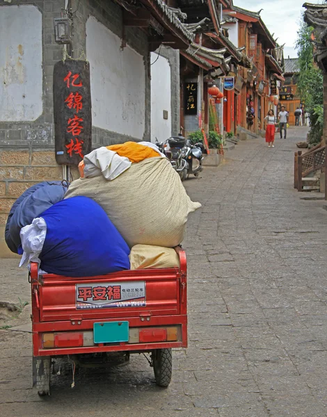 Motortrehjulingar med säckar på gatan i Lijiang — Stockfoto